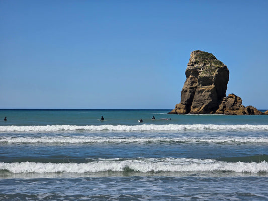 Photo of a New Zealand surf break and group of surfers on their boards in the water.