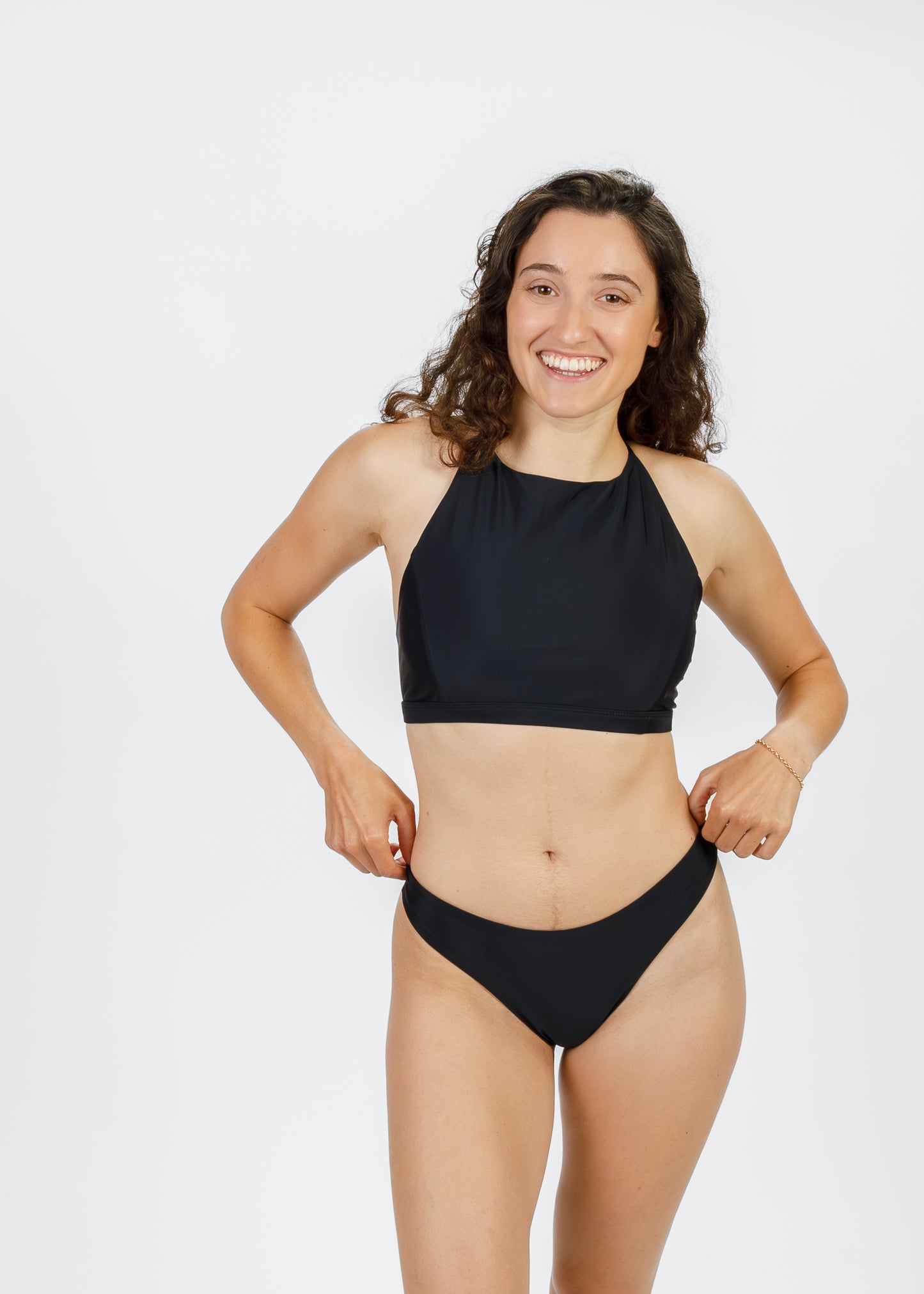 Front-facing image of woman wearing black high-cut bikini bottoms from Tamara, featuring a modern, minimalist design perfect for beach activities.