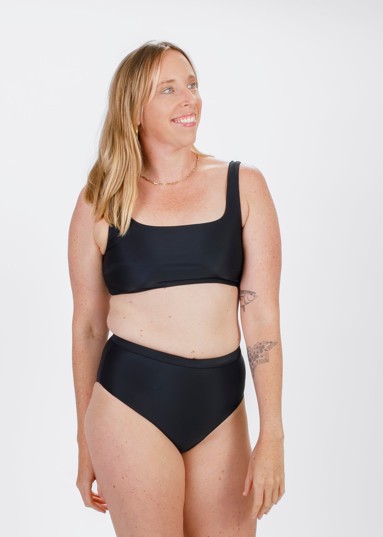 Woman modelling Tamara’s sleek black high-waisted bikini bottoms, offering comfortable coverage and a flattering fit, viewed from the front.