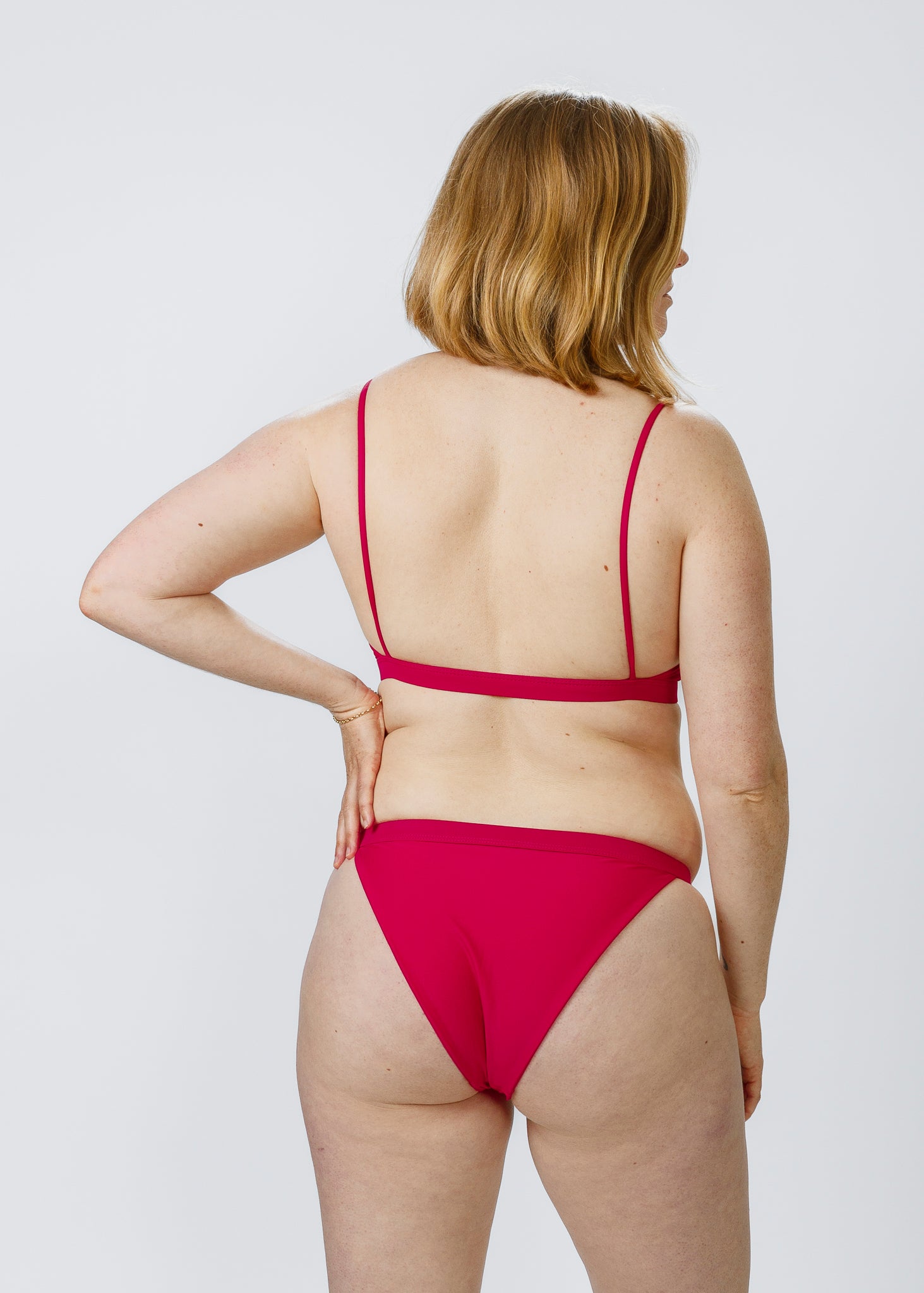 Back view of a woman wearing pink low-rise bikini bottoms by Tamara, highlighting the comfortable, flattering coverage and stylish cut.