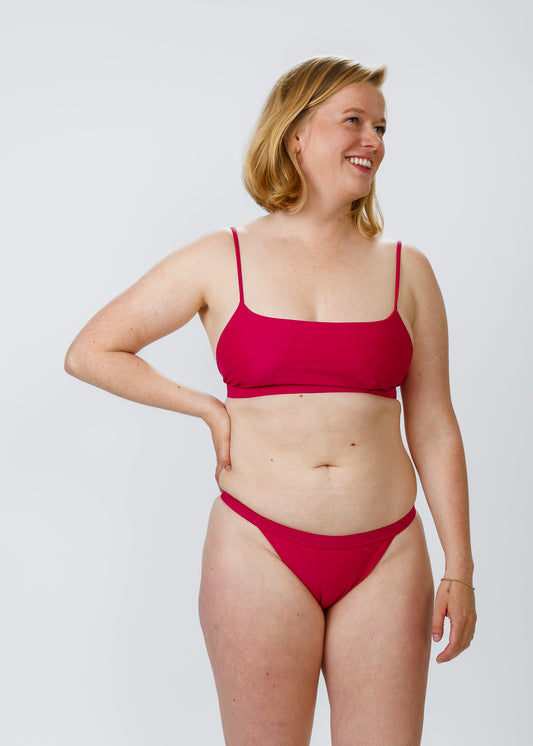 Front view of a woman confidently wearing sustainable pink low-rise bikini bottoms by Tamara, designed for comfort and style.